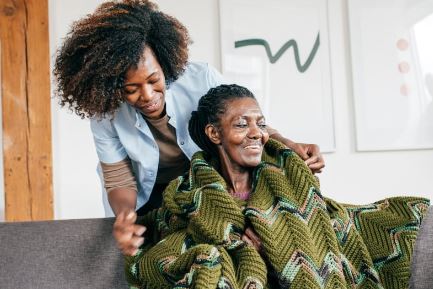 A caregiver wraps a blanket around a client